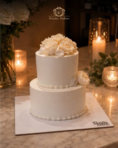 Elegant two-tier white wedding cake with handcrafted white roses