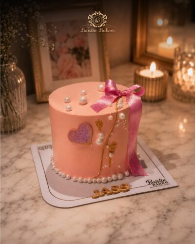 Elegant pink designer cake with pearl decorations and ribbon topper