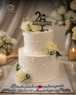Elegant silver jubilee anniversary cake decorated with white roses, pearls, and anniversary topper.
