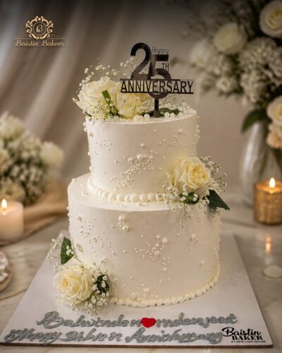 Elegant silver jubilee anniversary cake decorated with white roses, pearls, and anniversary topper.