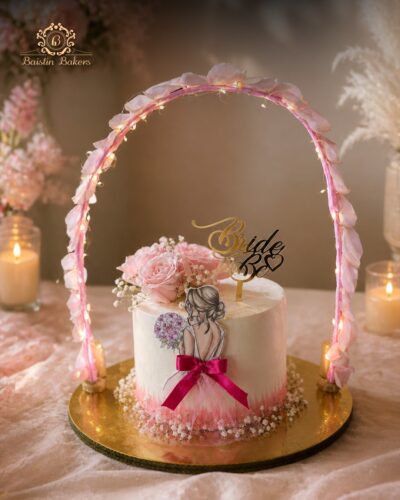 Elegant Bride To Be cake with floral decorations and illuminated arch design.